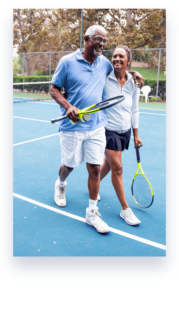 couple walking on tennis court with tennis rackets